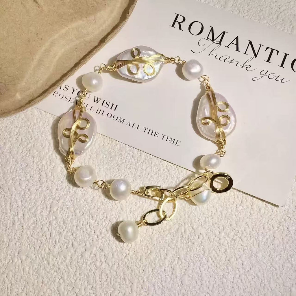 Handmade pearl shell bracelet featuring freshwater pearls and gold wire wrapping, ocean-inspired jewelry laid on a soft neutral background