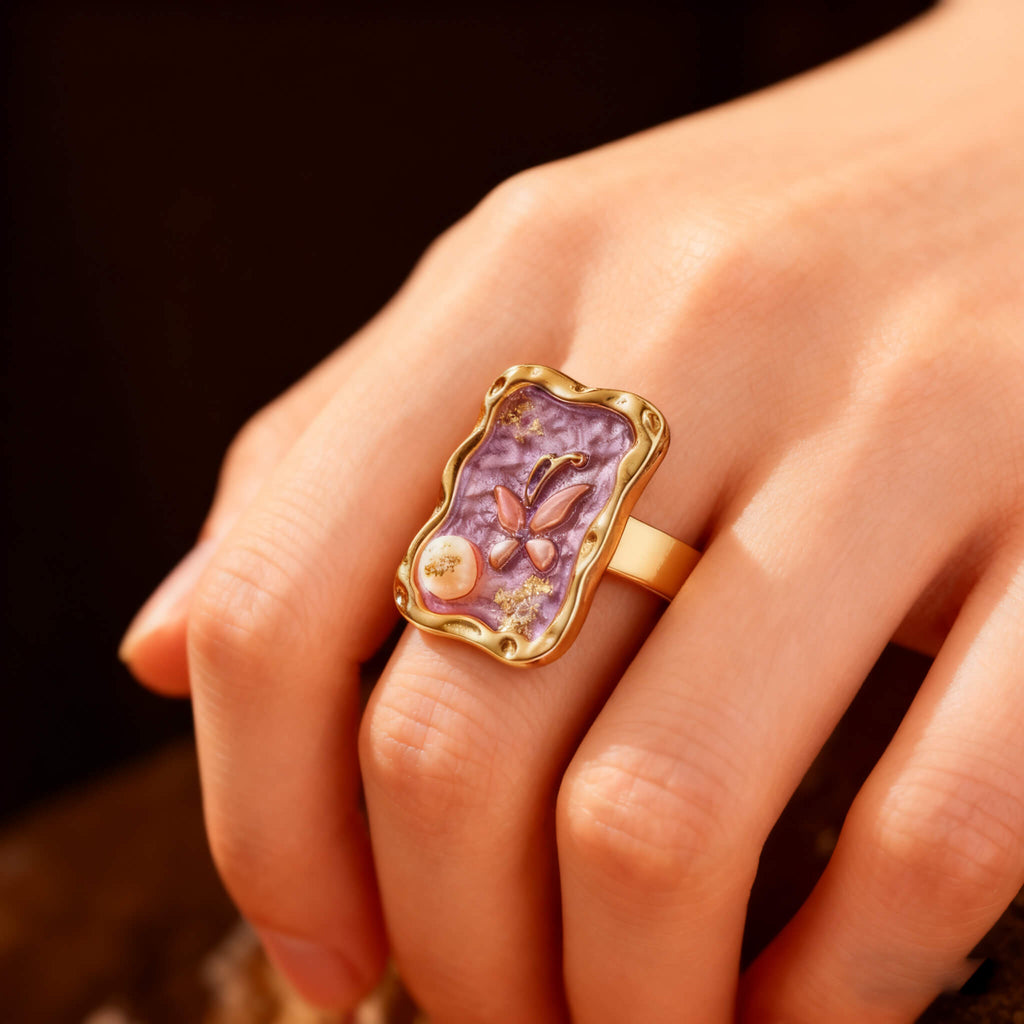 Luxury gold ring showcasing a butterfly design on a purple enamel surface with pearl embellishment.