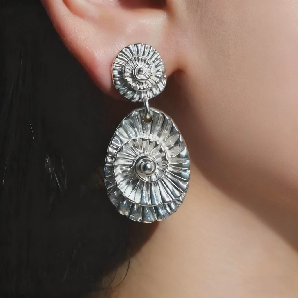 Boho-style silver seashell earrings with spiral and layered detailing.