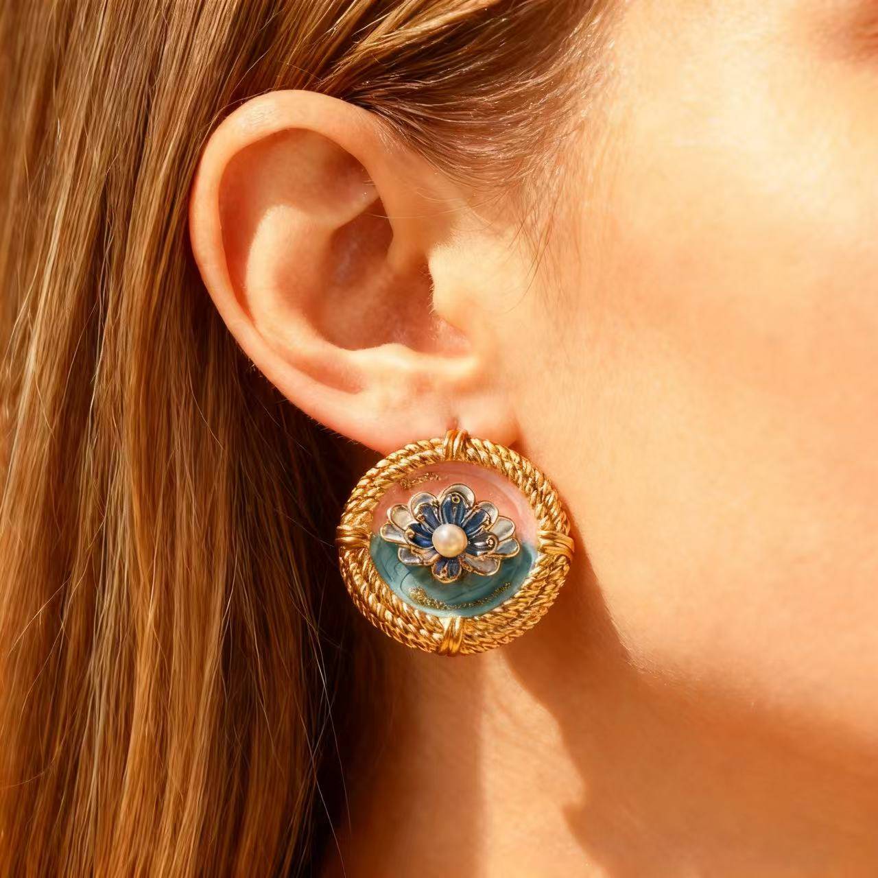 Close-up of an ear wearing a decorative gold earring with floral design.