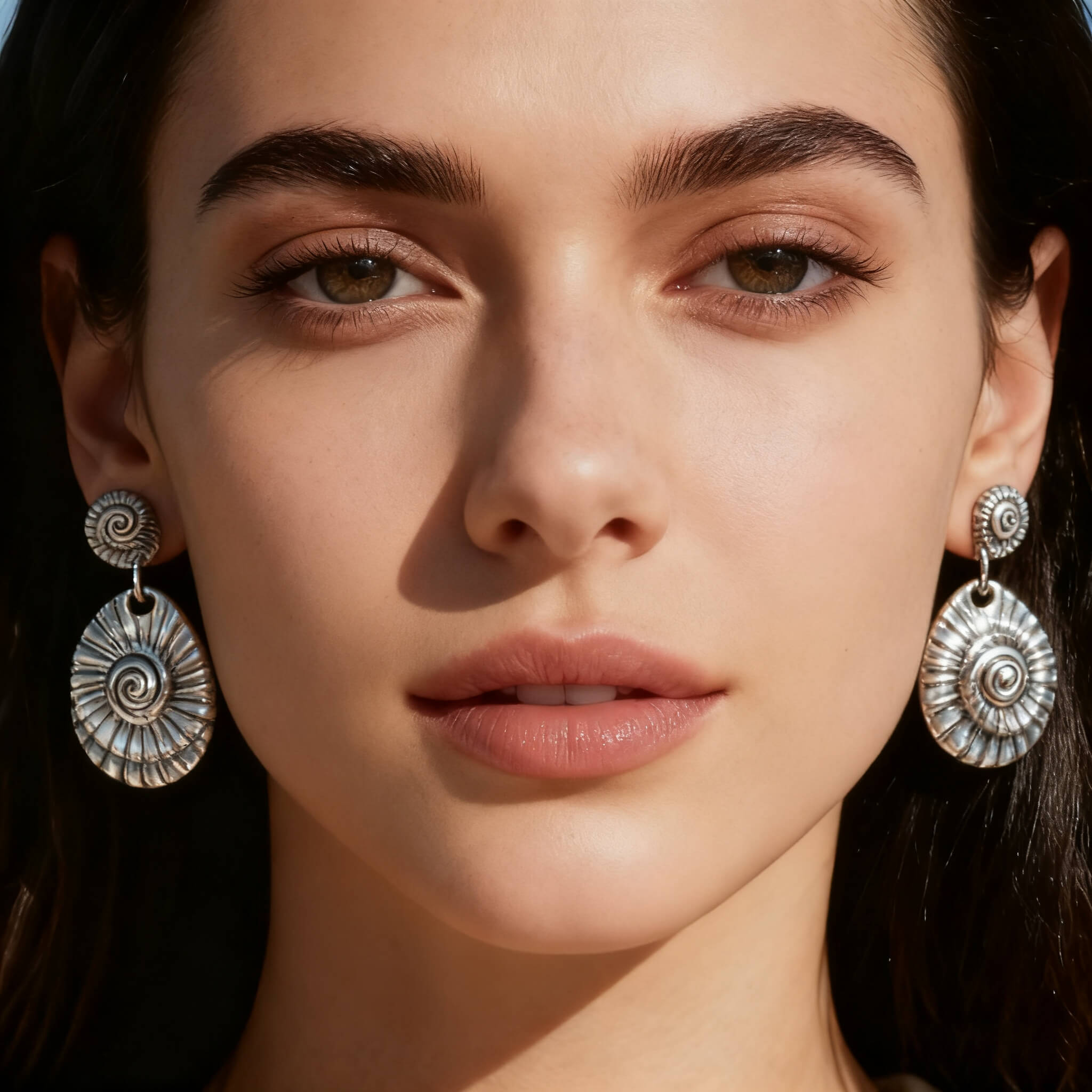 Artistic silver shell dangle earrings featuring a textured swirl pattern.