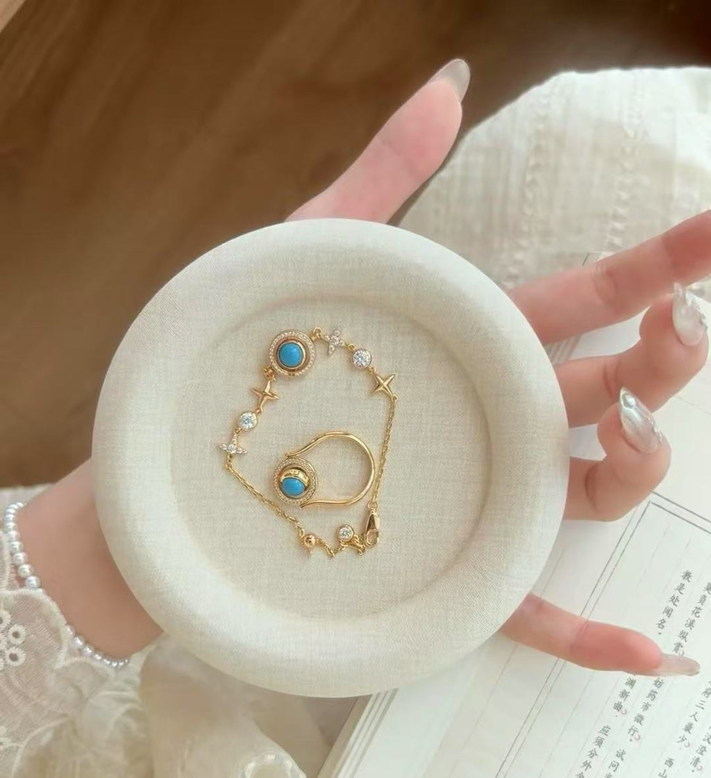 Gold bracelet with turquoise stones on a white dish held by a hand.