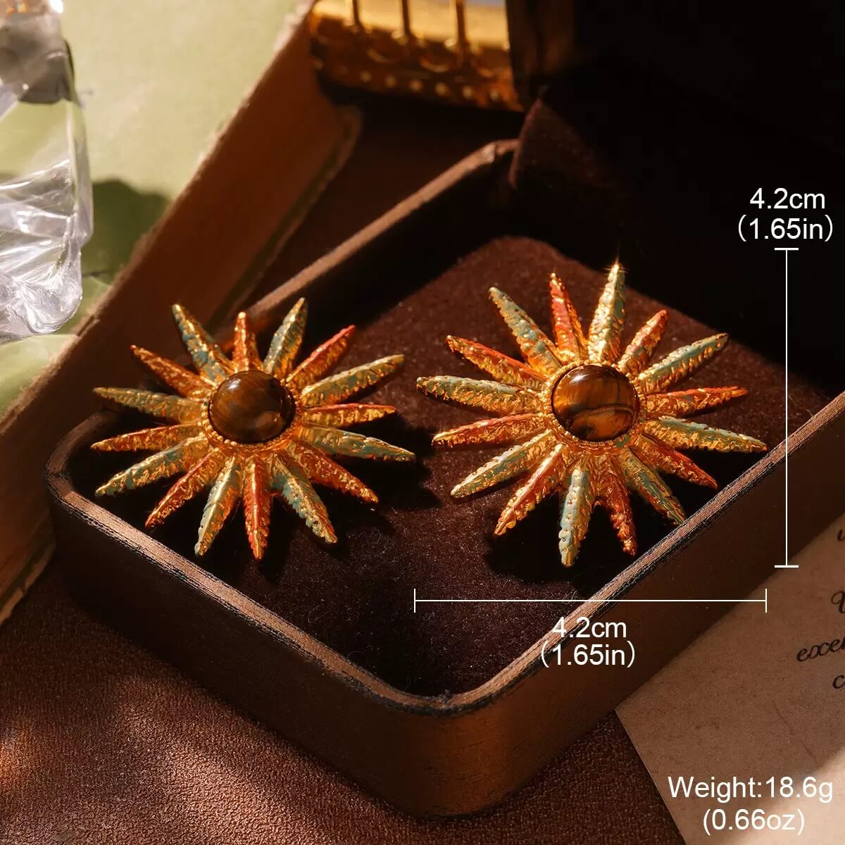 Retro-style gold sun ray earrings featuring detailed texture and amber gemstone centerpiece.