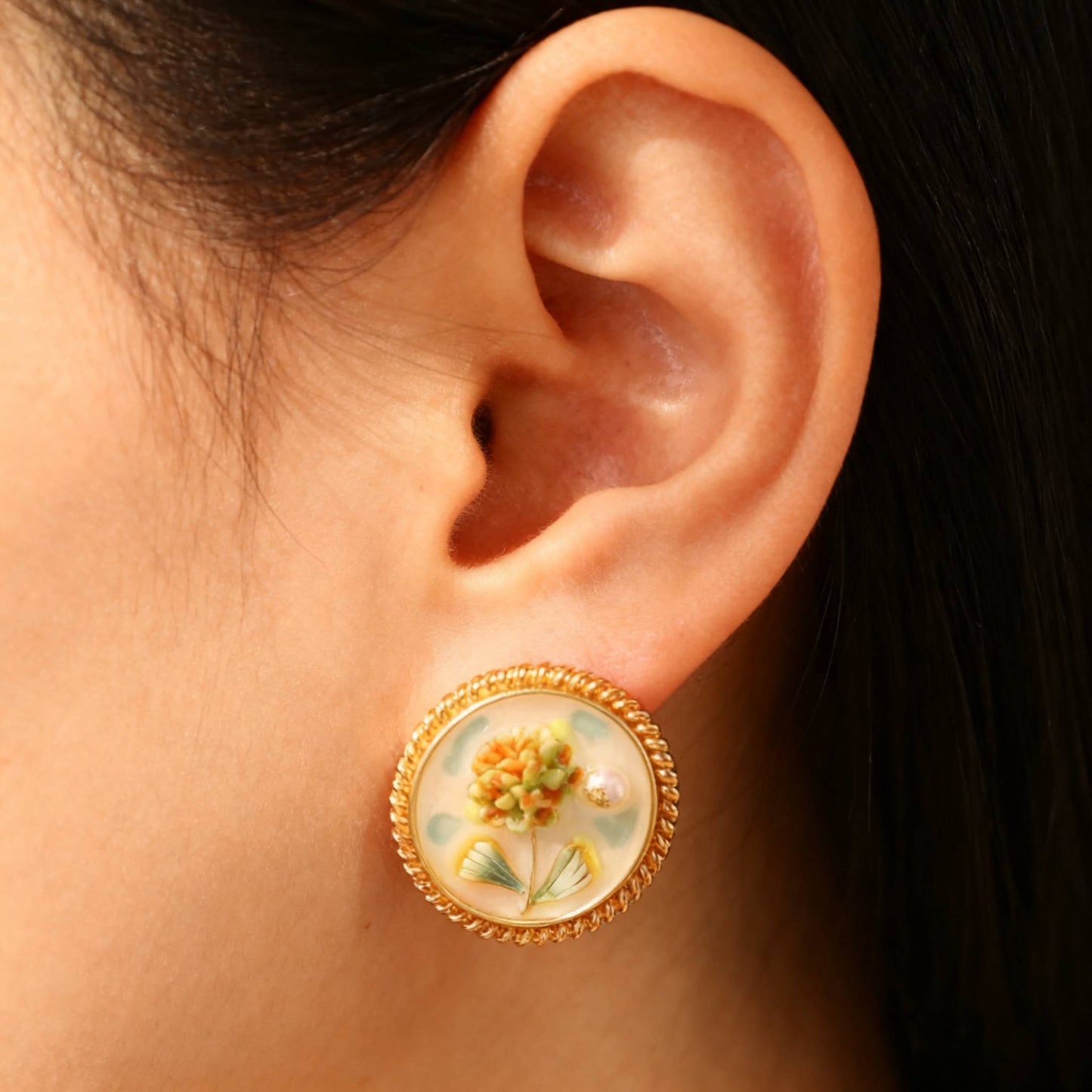 Handcrafted hydrangea enamel earrings with gold round frame and soft colors- wearing