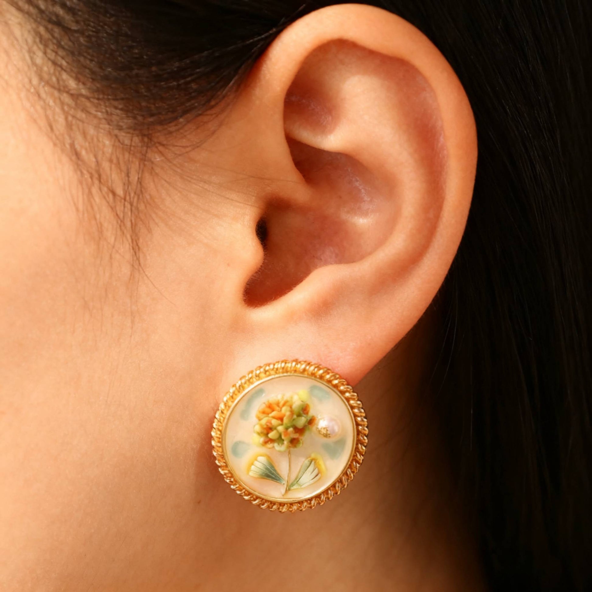 Handcrafted hydrangea enamel earrings with gold round frame and soft colors- wearing