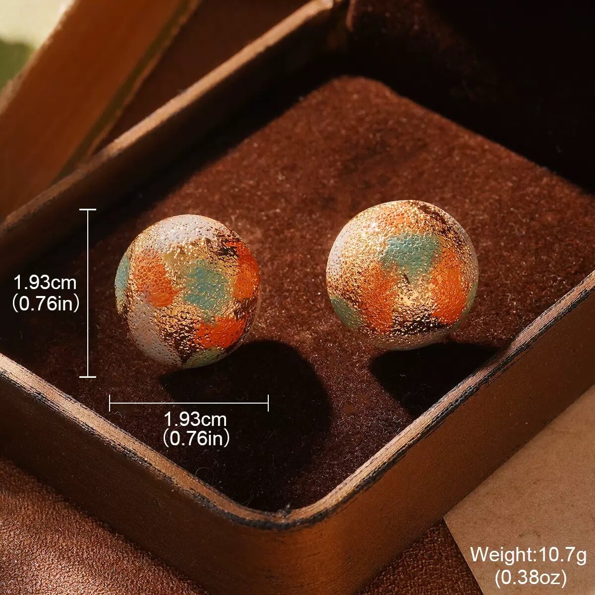 Baroque-style gold frame earrings featuring delicate floral painting, displayed in warm holiday lighting.