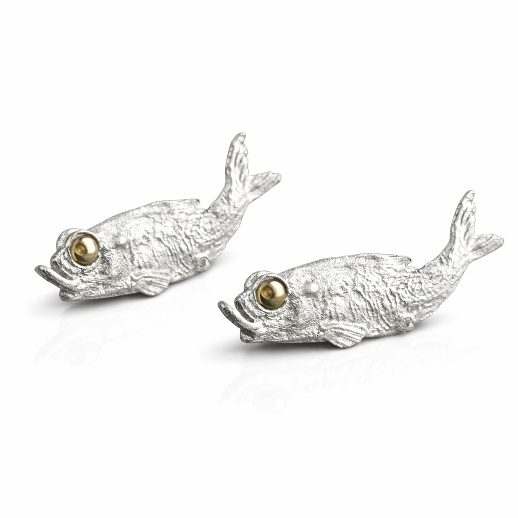 Two silver fish-shaped necklace part with gold eyes on a white background