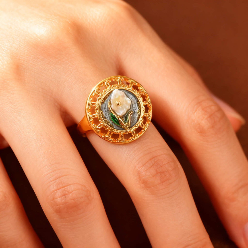 Vintage-style gold ring featuring a pearl blossom and intricate floral design.