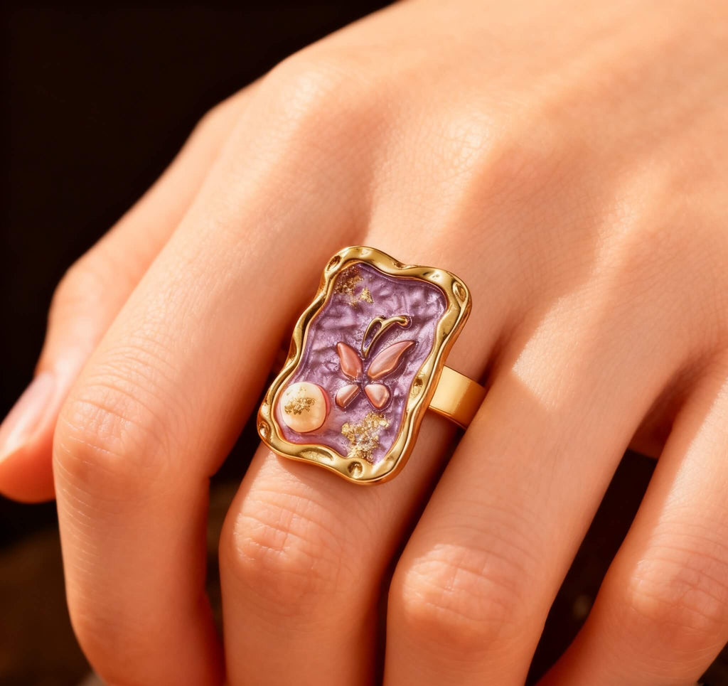 Close-up of a gold butterfly ring with shimmering purple enamel and pearl detail.