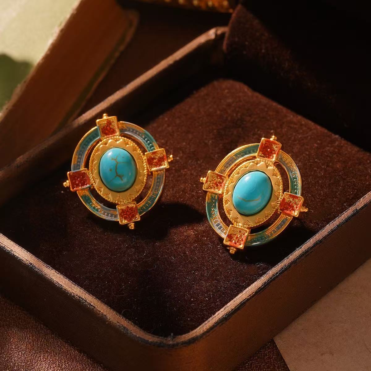 Gold effect earrings with turquoise stones on a brown velvet surface