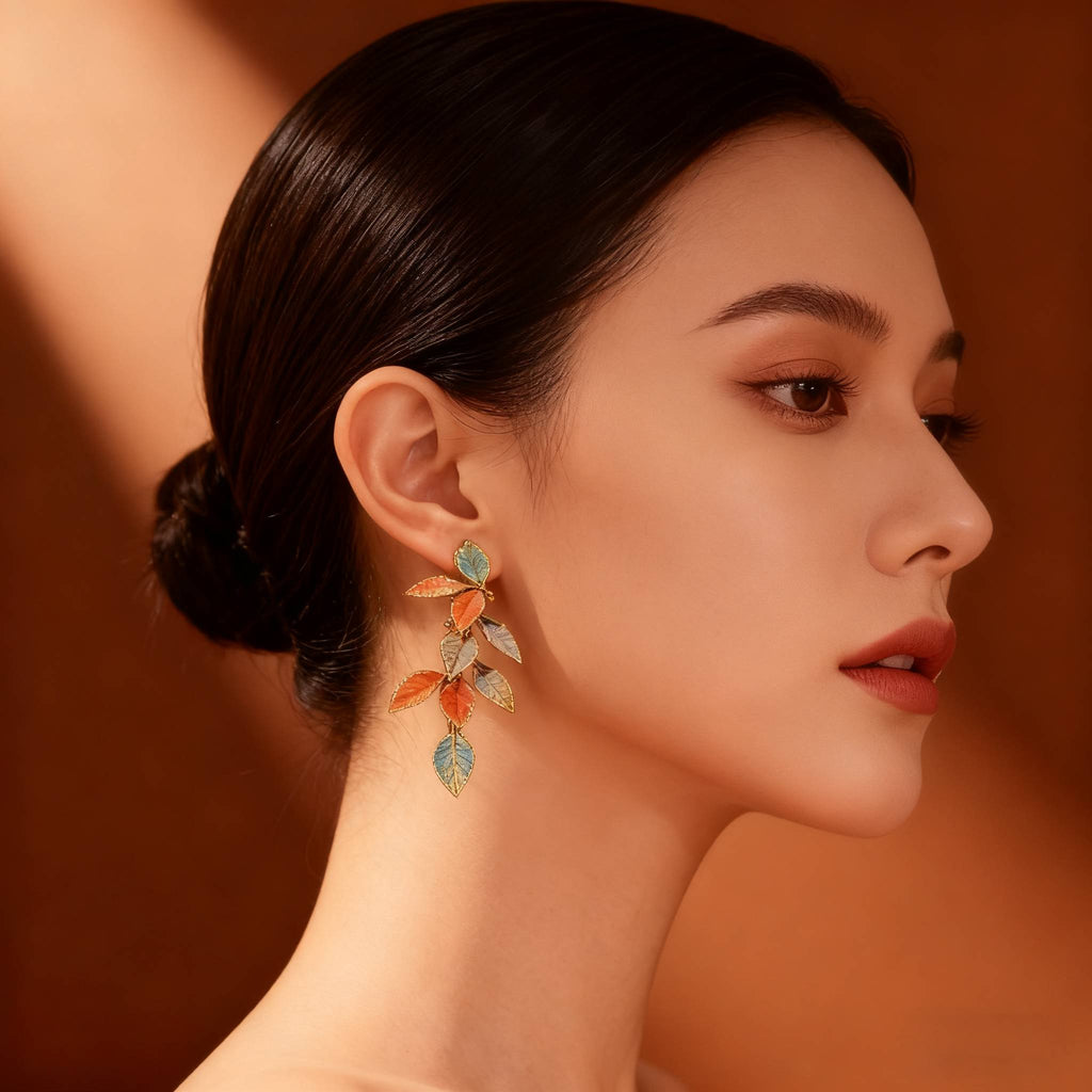 Lightweight statement earrings with cascading enamel leaves in orange and teal.