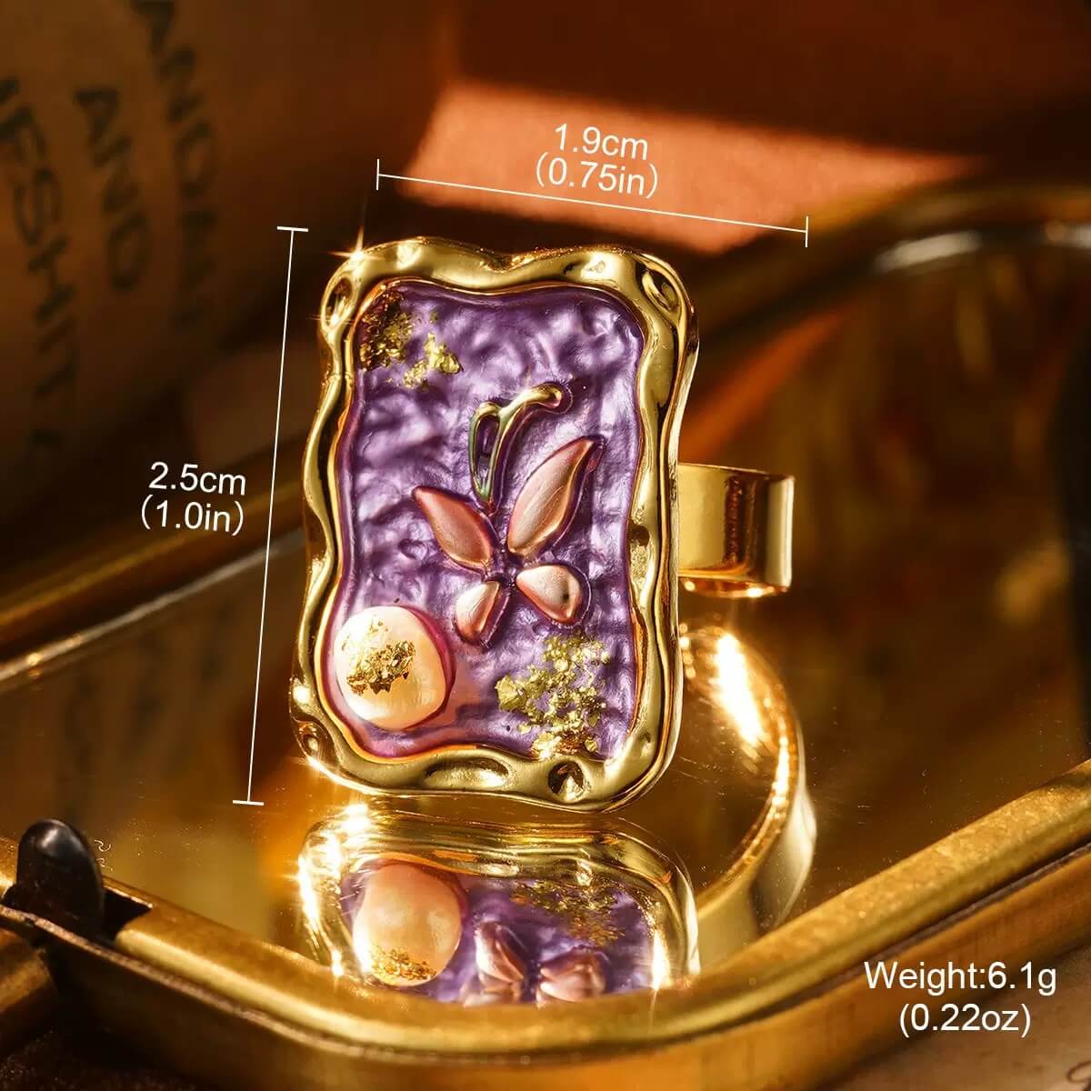 Handcrafted gold butterfly ring with textured purple enamel and decorative details.