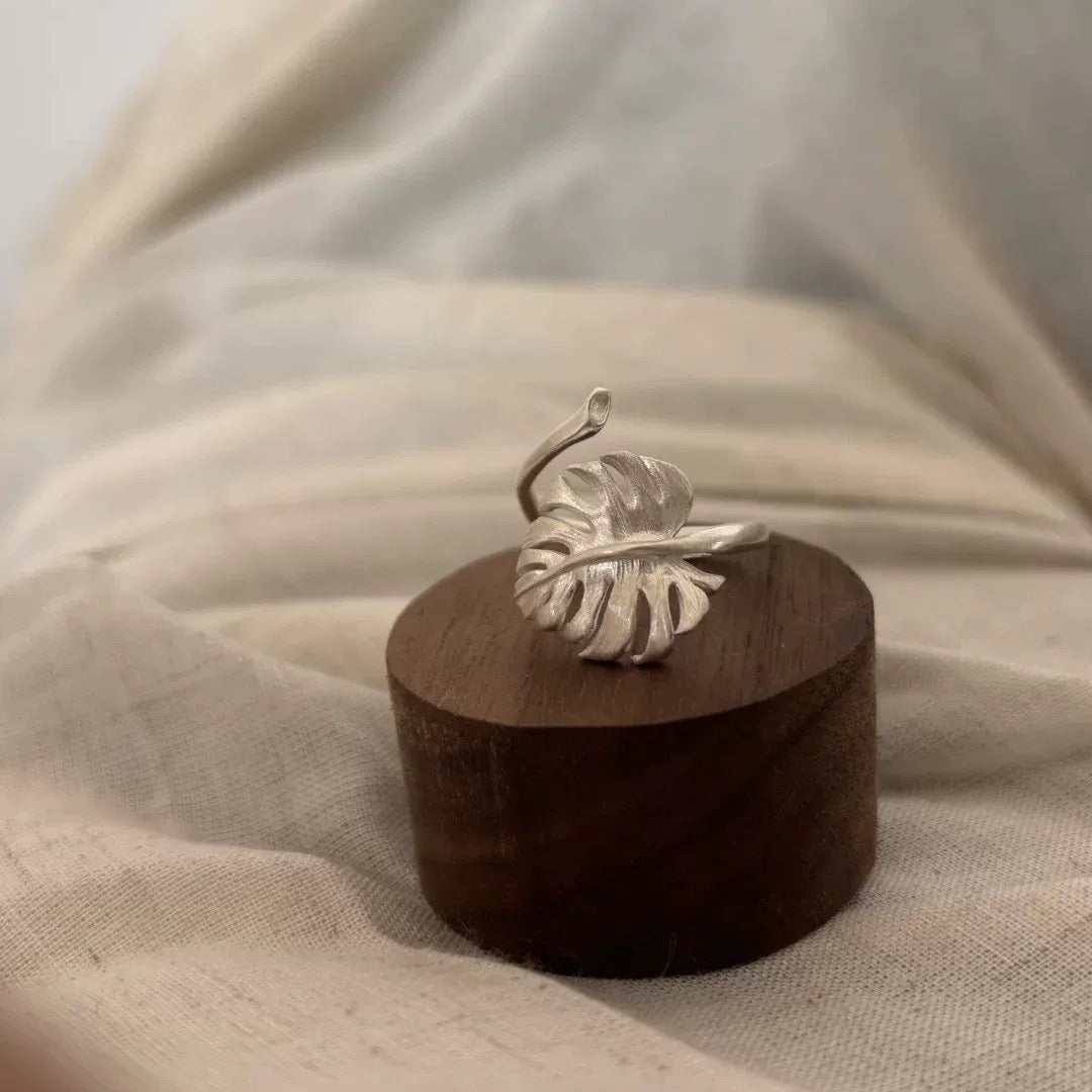 Botanical-style silver leaf ring with detailed monstera shape, shown in a soft natural setting.