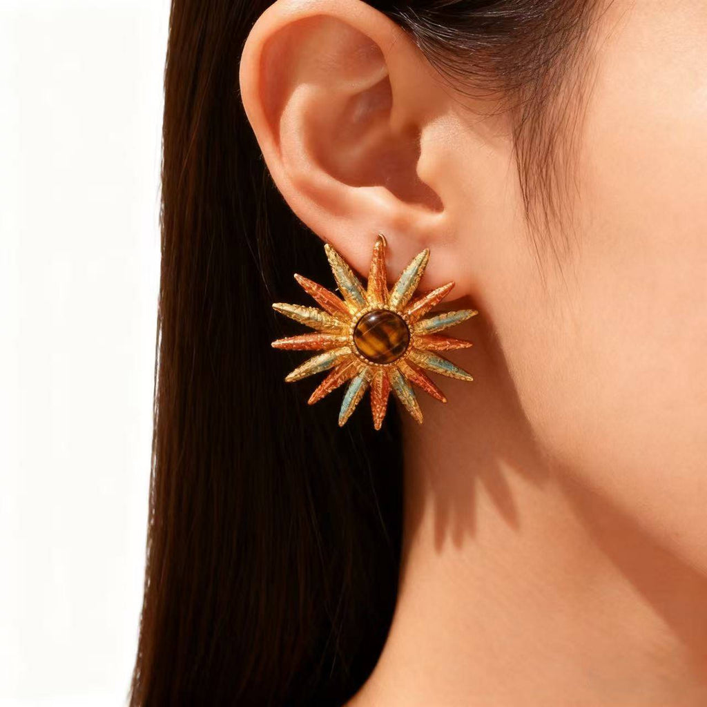 Elegant gold sunburst earrings with warm amber stone, shown in classic jewelry packaging.”