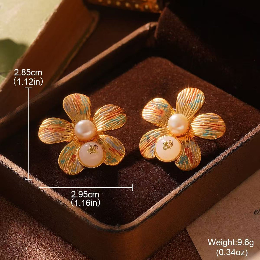 Elegant gold floral stud earrings with textured petals and pearl accents