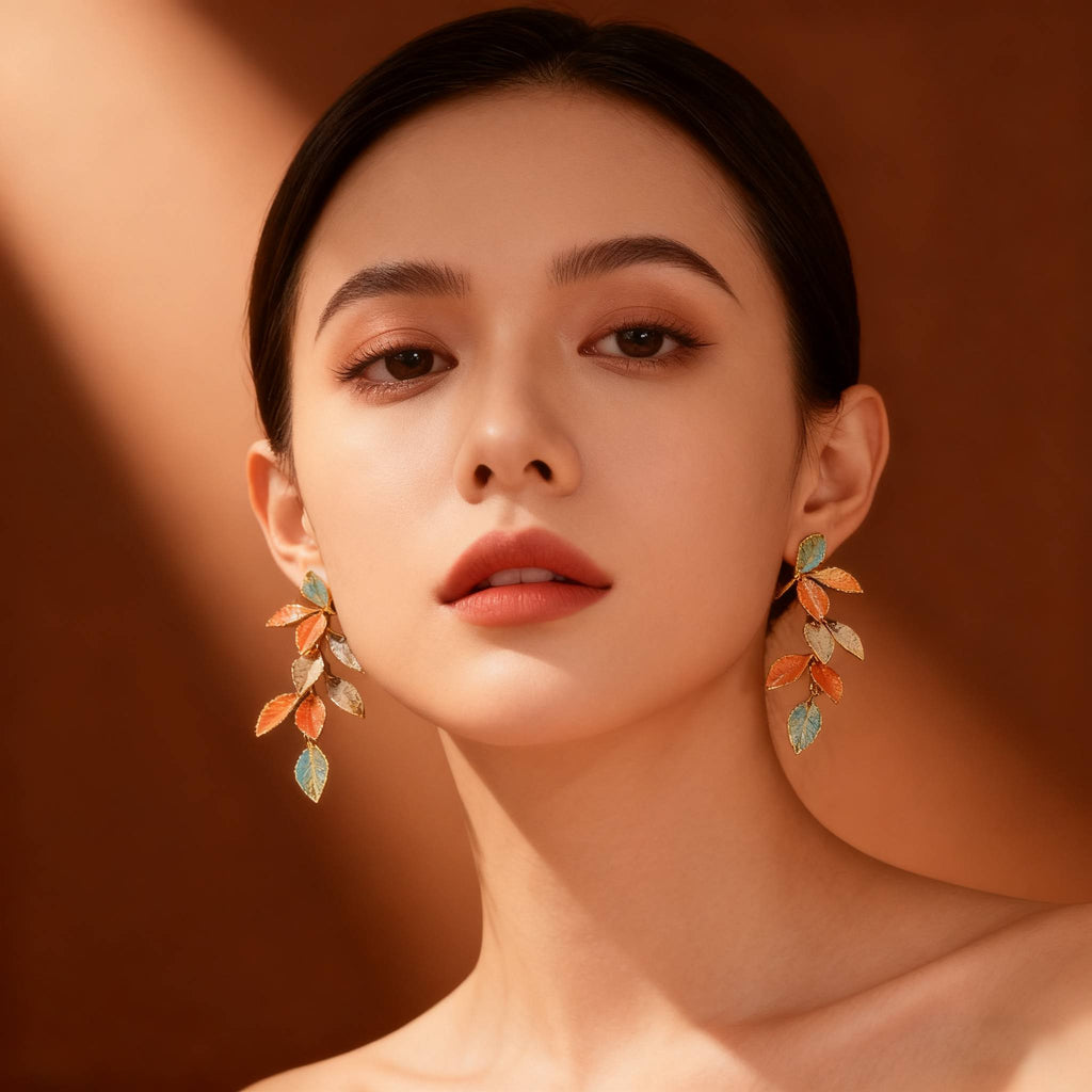Nature-inspired dangle earrings designed with textured gold leaf frames and colorful enamel.