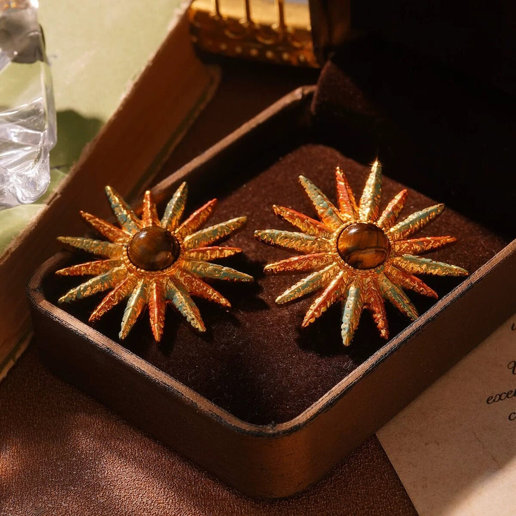Vintage gold sunburst earrings with amber center stone displayed in a velvet jewelry box.
