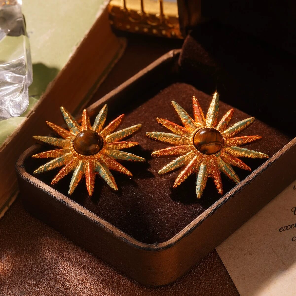 Vintage gold sunburst earrings with amber center stone displayed in a velvet jewelry box.