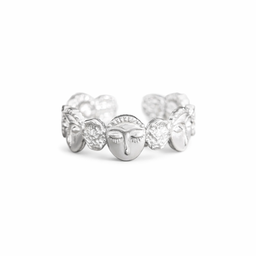 Silver ring with face design on a white background